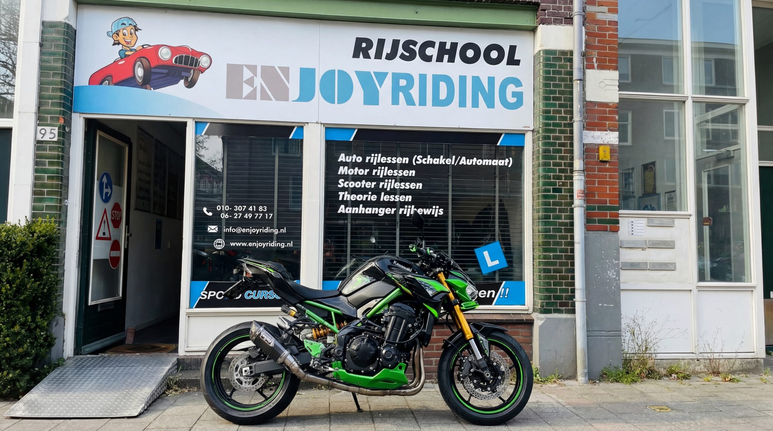 Groene Kawasaki motor voor rijschool Enjoyriding met cartoon logo en services op storefront